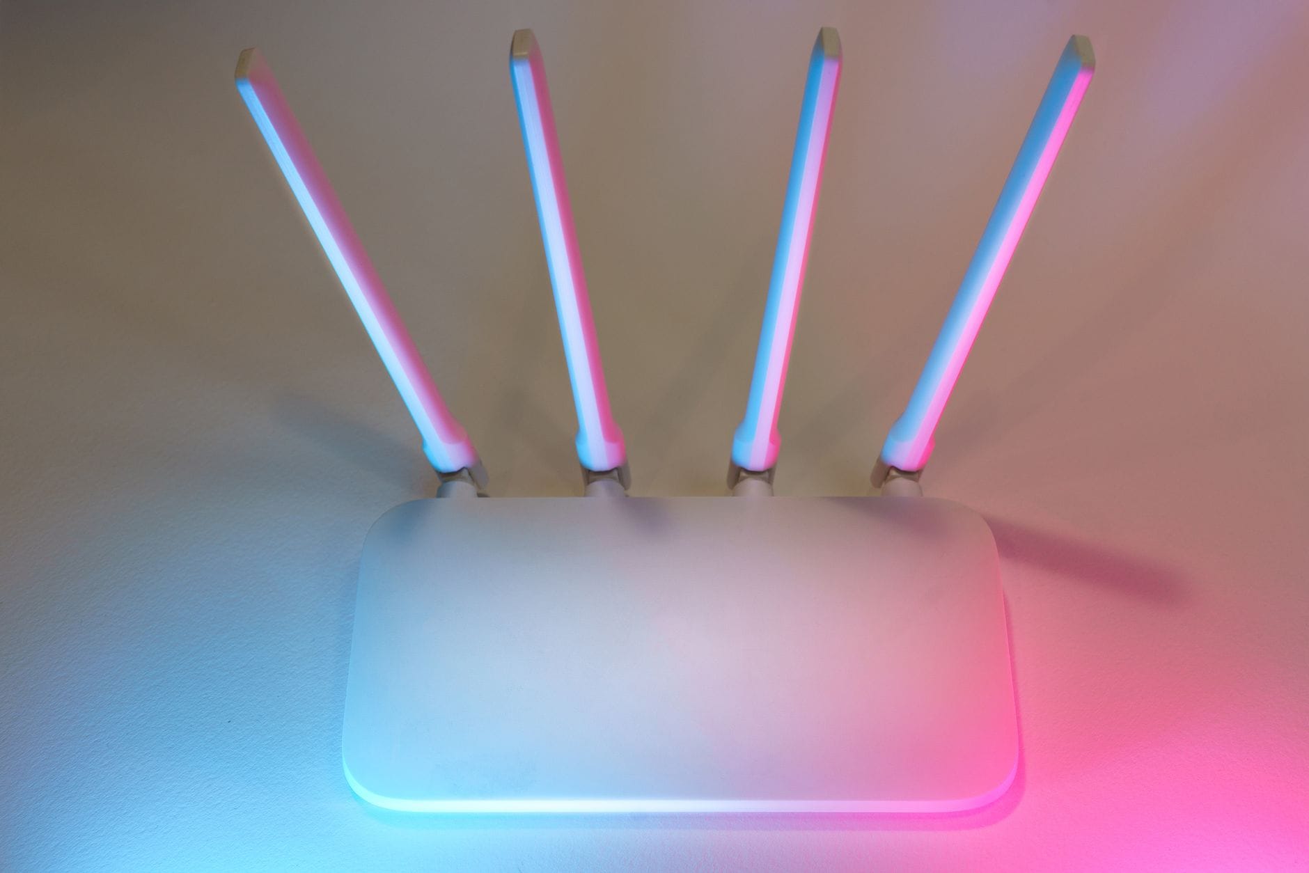 Biały router WiFi z czterema antenami podświetlony na niebiesko i różowo