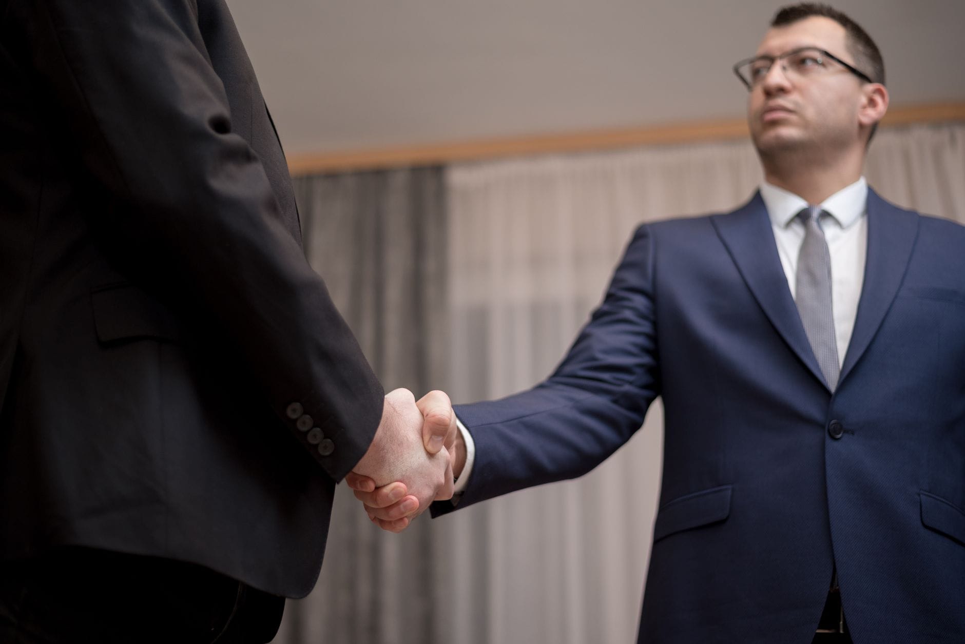 Jak wybrać hurtownię do współpracy w modelu B2B, aby zwiększyć marżę i bezpieczeństwo dostaw Dwóch biznesmenów w garniturach podaje sobie dłonie podczas spotkania